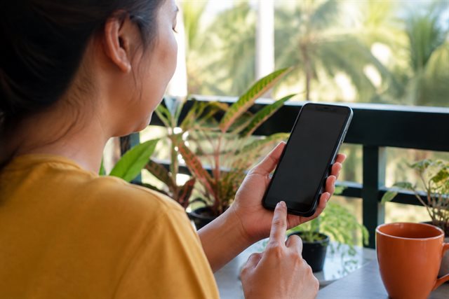 A woman pausing while using her phone on a home balcony